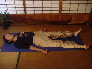 A person laying face-up on a yoga mat, relaxed.