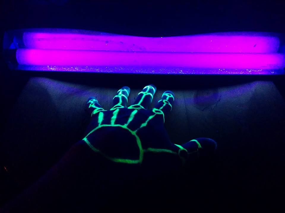 A blacklight glowing purple, illuminating lime green highlighter which forms a somewhat skeletal pattern on the back of my hand.